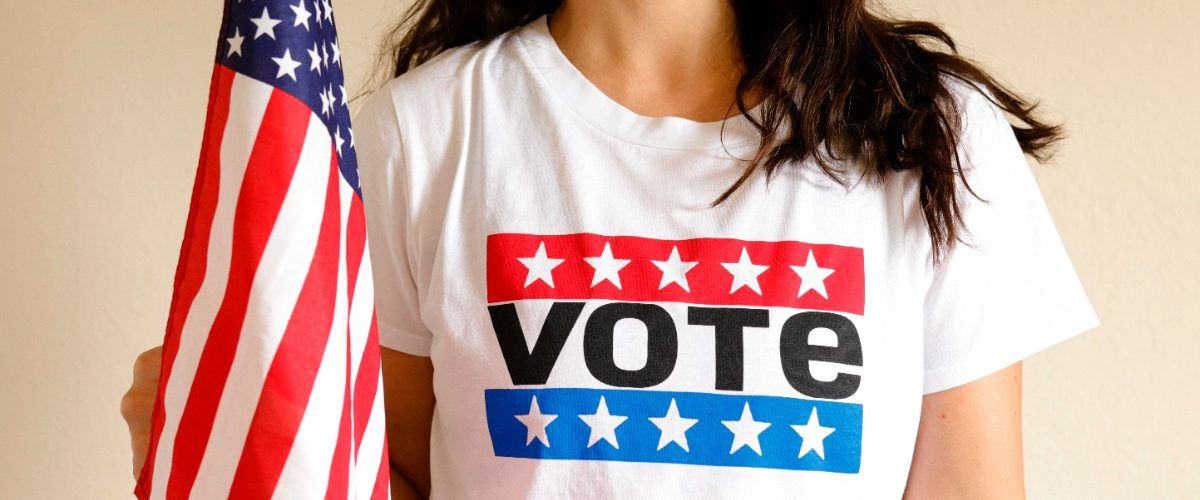 woman wearing a vote tshirt and waving a us flag